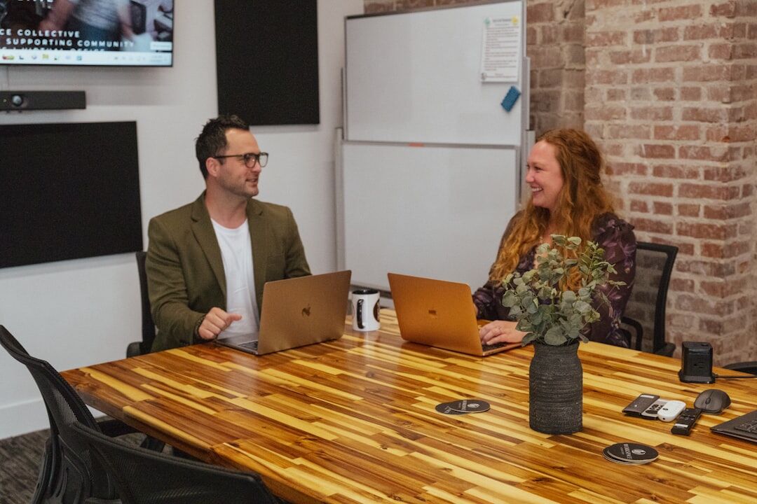 Diverse media team having a collaborative meeting around a table with laptops